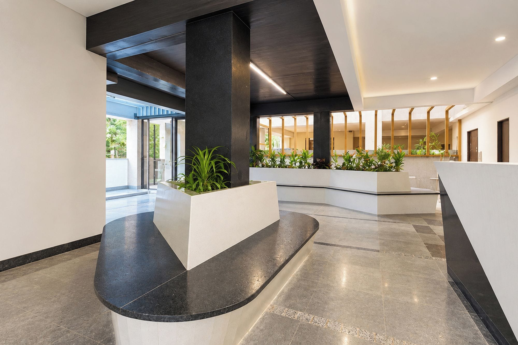 Una hall moderna con una reception a forma di arco, un pilastro centrale e vista sull'esterno.