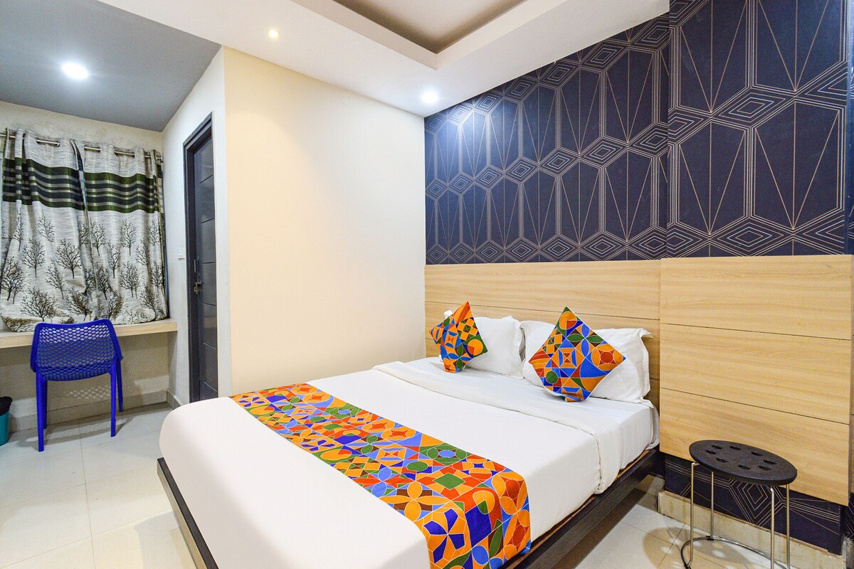 A hotel room with a bed, a chair, a small table, and a patterned wall.