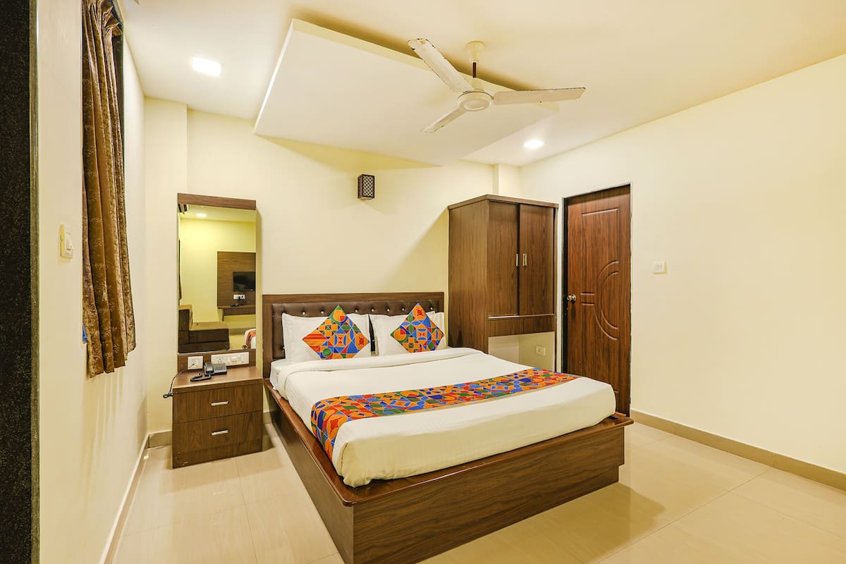 A bedroom with a bed, a wardrobe, a nightstand, a ceiling fan, and a mirror.