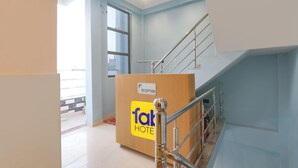 A reception desk with a sign indicating a reception area, a staircase with metal railings, and a sign on the wall stating "No Time 0 AM". - Fabhotel Hridyam Madhuram (Faizabad)