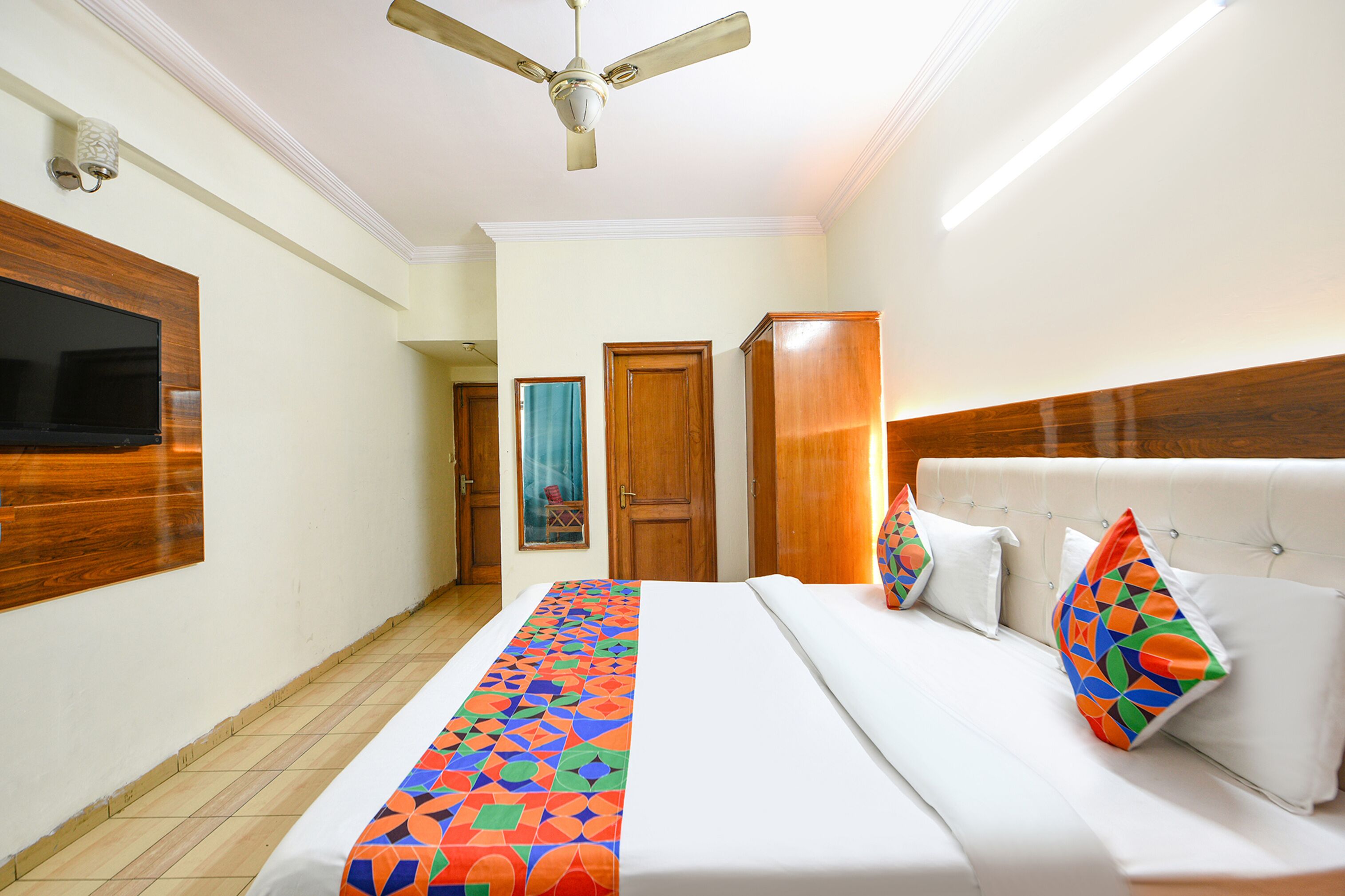 Une chambre d’hôtel équipée d’un lit, d’un ventilateur de plafond, d’une télévision et de panneaux de bois aux murs.