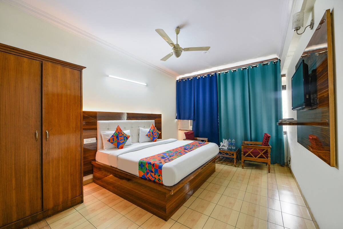A hotel room with a wooden bed, a ceiling fan, a TV, and a desk with a chair.