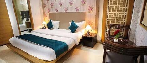 A hotel room with a large bed, two bedside tables with lamps, a wooden chair, and a decorative wall panel.