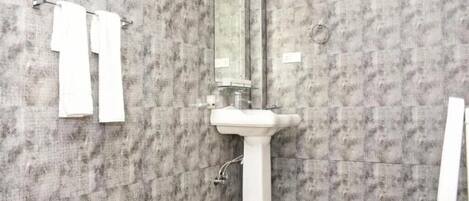 Un baño con pared de diseño de mármol, un lavamanos blanco y un espejo grande.