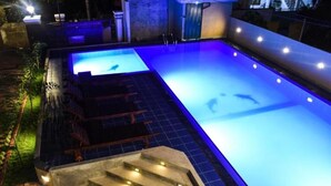 A swimming pool with steps leading into it, surrounded by a garden and a building. - Mamma Raji Hotel (Negombo)