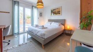 A bedroom with a bed, a desk, a chair, a lamp, and a plant.