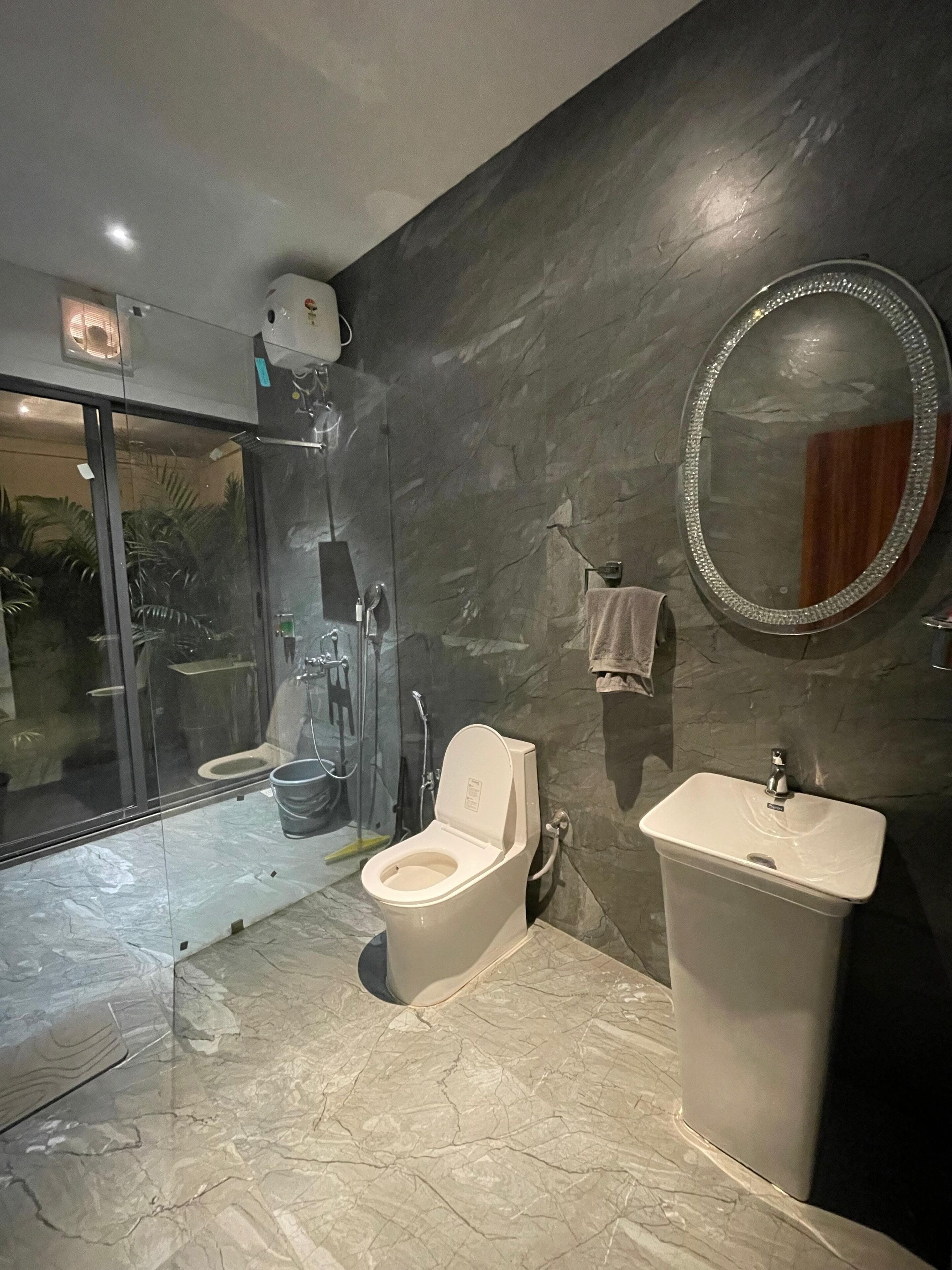 A modern bathroom with a glass-enclosed shower, a toilet, and a sink.