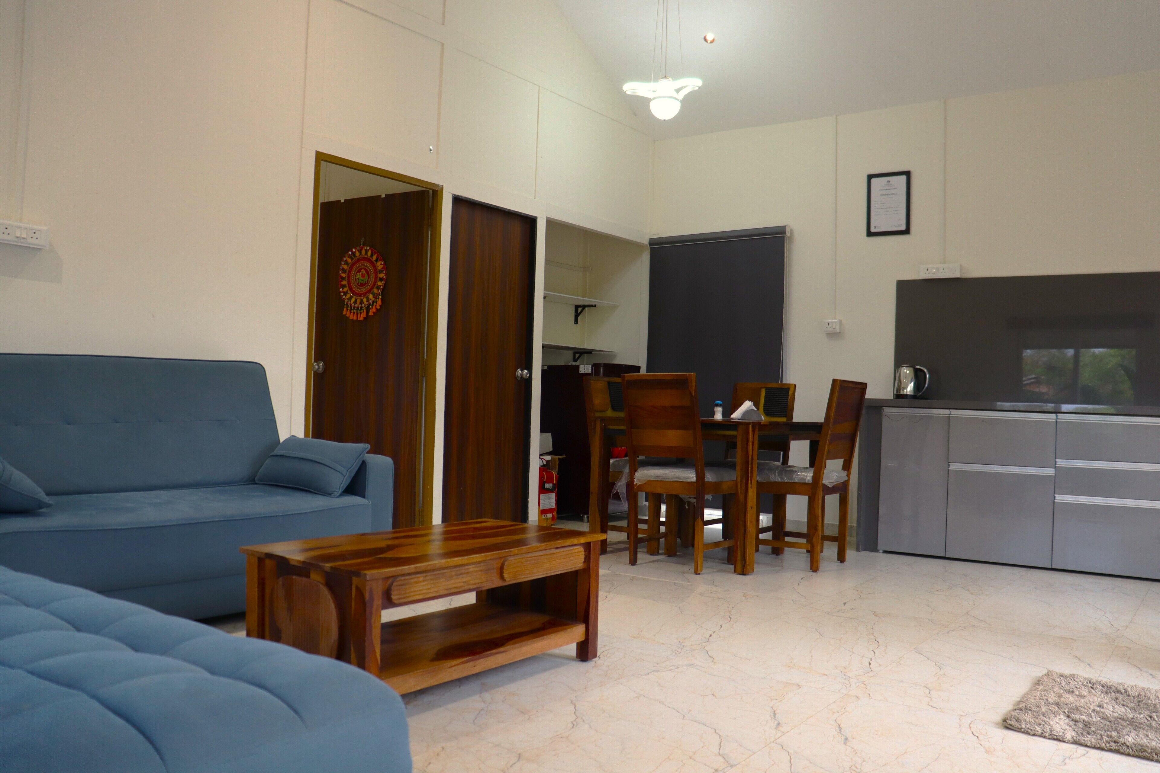 Una sala de estar con sofá azul, una mesa de centro de madera y un comedor con sillas y una mesa.