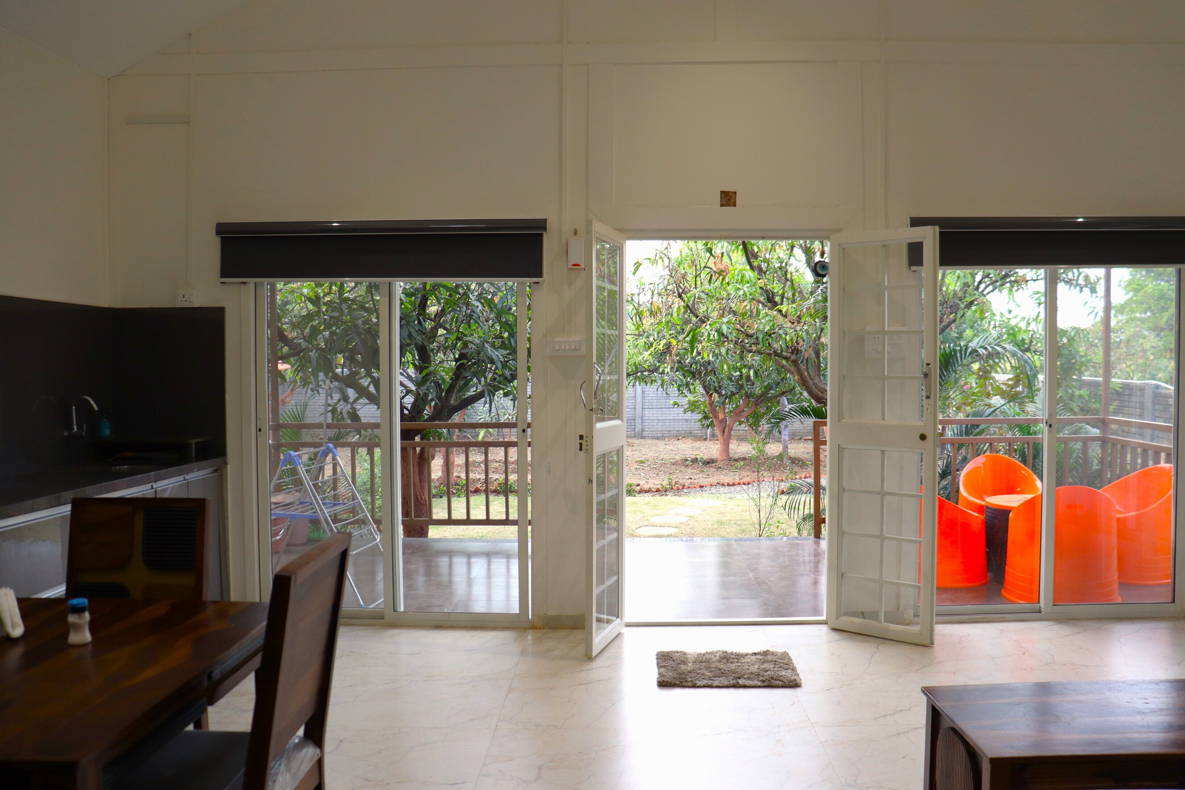 A spacious living area with a sliding glass door leading to a patio with outdoor furniture and a view of greenery.