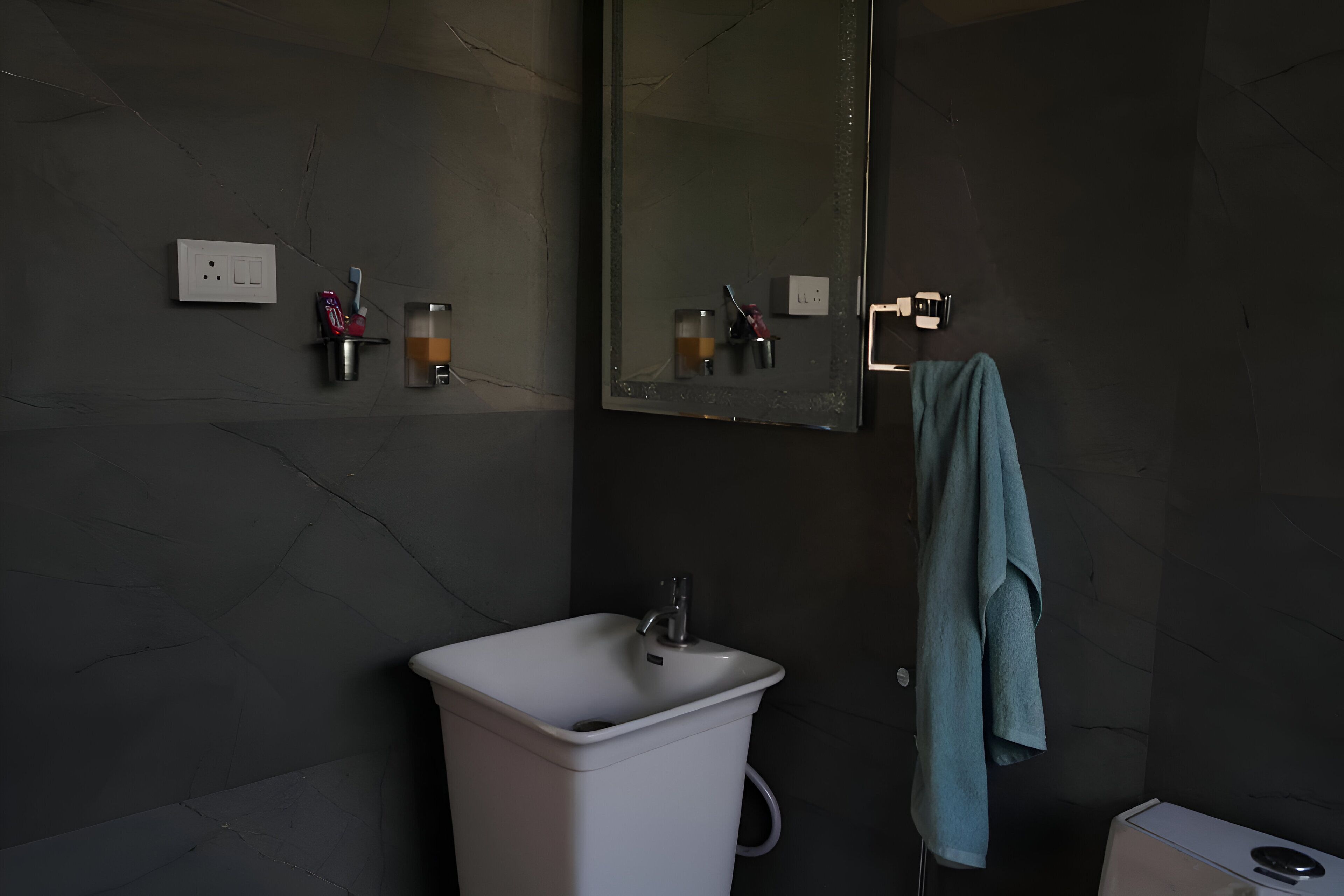 Een badkamer met een witte wastafel, een spiegel en een handdoek aan de muur.