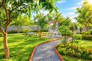 A garden with a swing set, a bench, and a gravel path.