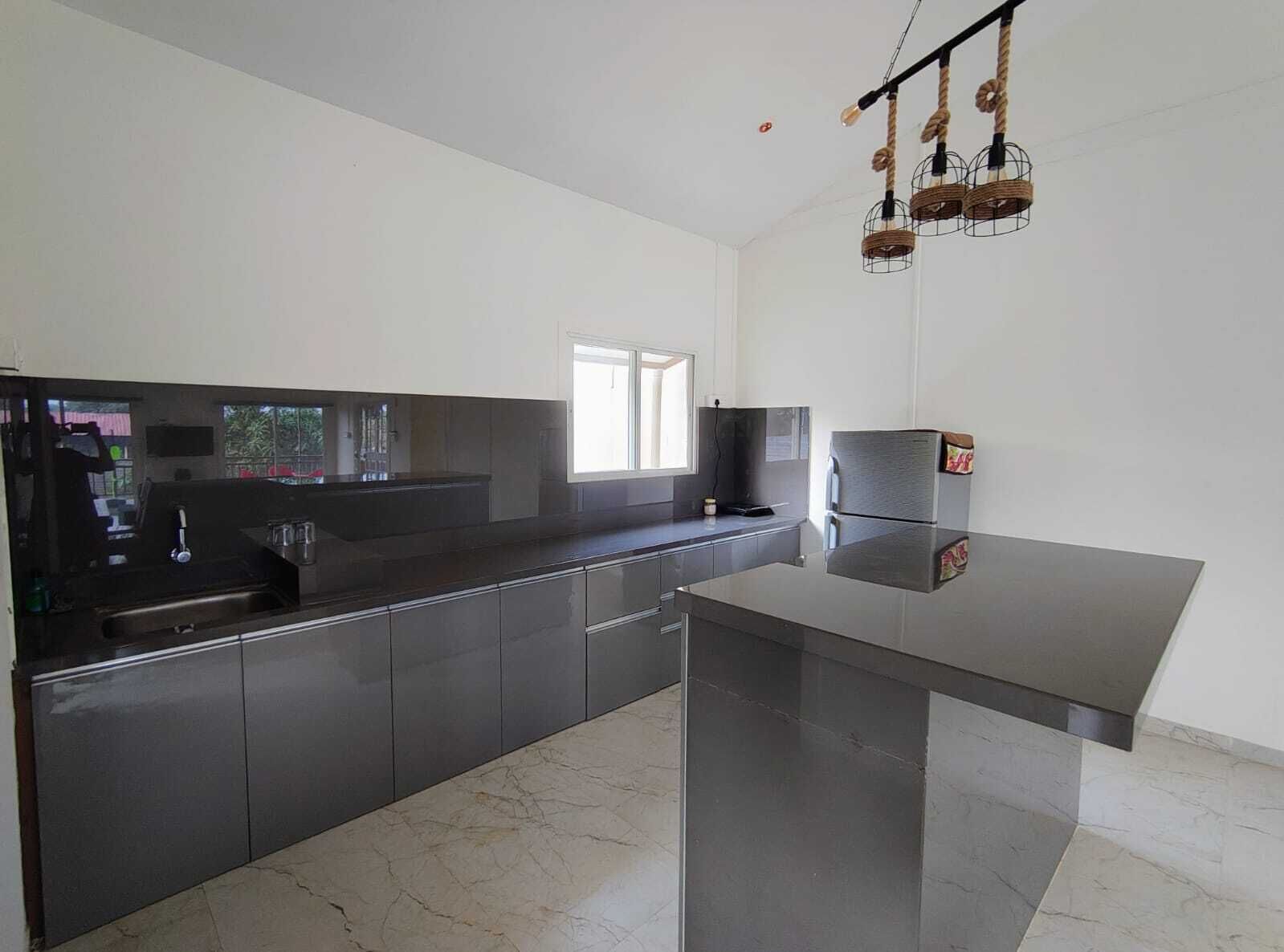 A modern kitchen with dark cabinetry, a large island, and a unique rope light fixture.