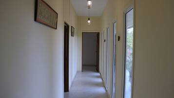 En gang med billeder i rammer på væggene, en hængende lampe og en dør for enden.