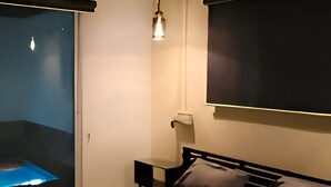 A bedroom with a bed, bedside table, and a wall-mounted TV. - Mango Shack Villa (Trimbak)