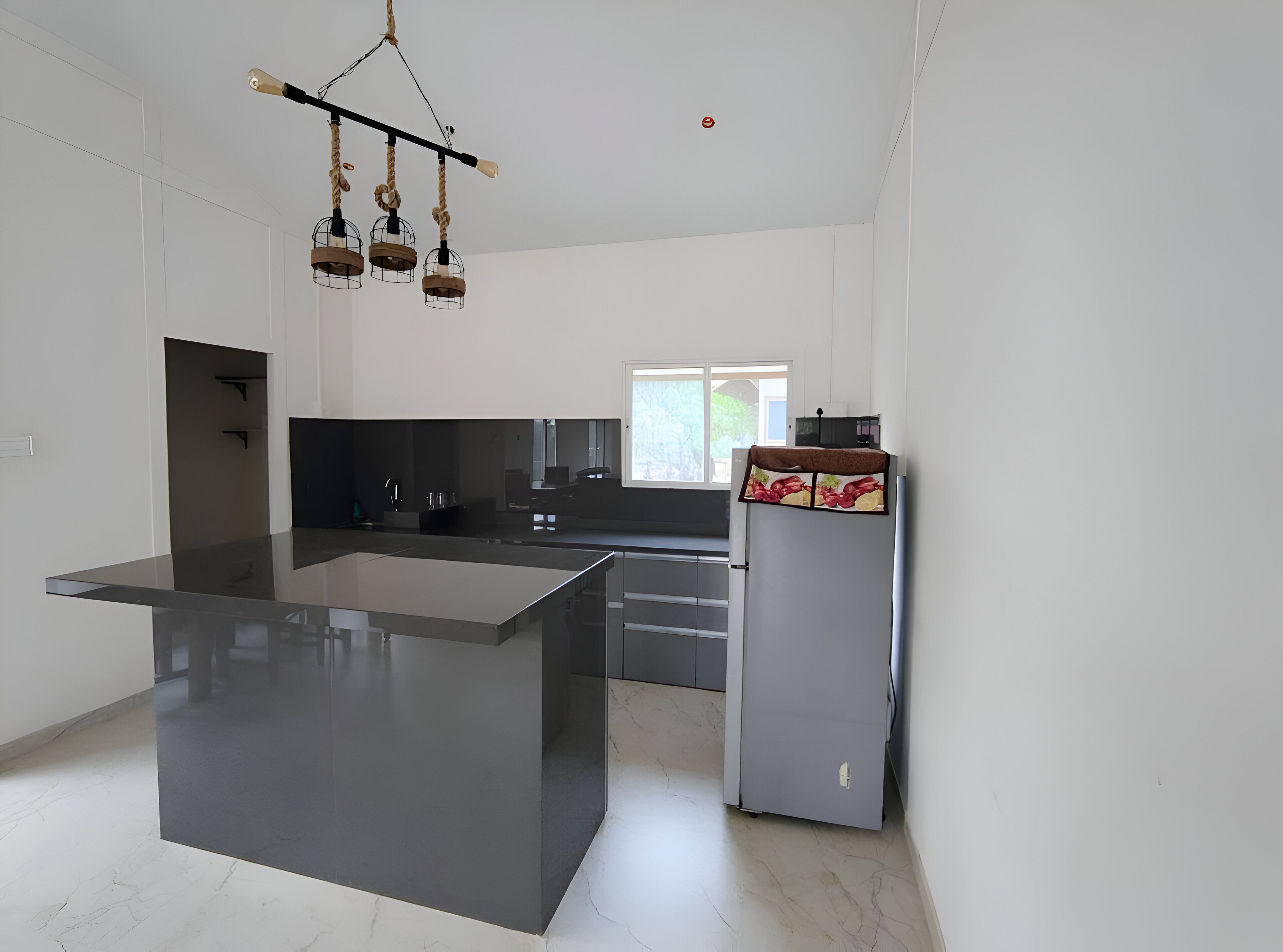 Una cocina moderna con una isla central, encimeras oscuras y un refrigerador decorativo.