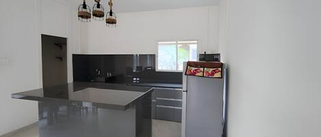 Una cocina moderna con una isla central, encimeras oscuras y un refrigerador decorativo.