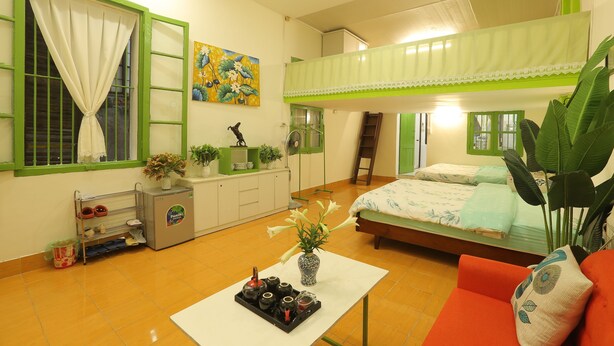Ein Schlafzimmer mit Etagenbett, einem kleinen Tisch mit Blumenvase, einem Schuhregal und einer Heizung.