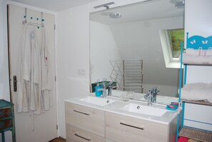 A bathroom with a double sink, a mirror, and a towel rack.