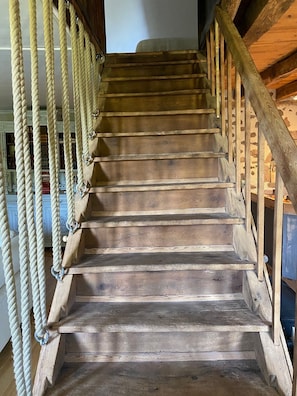 Una escalera de madera con barandilla y balaustres de cuerda.