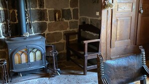 Una habitación rústica con chimenea de piedra, una mesa de madera y una silla de madera.