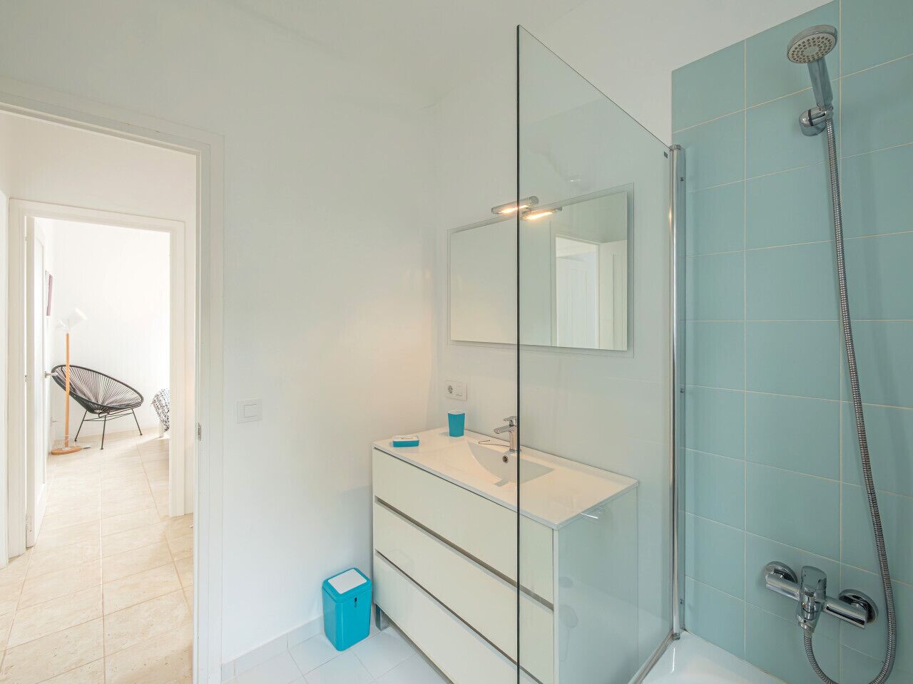 A modern bathroom with a glass shower enclosure, a white sink, and a mirror.