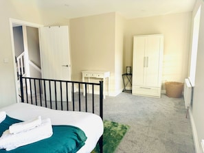 A bedroom with a bed, a desk, a wardrobe, and a staircase. - 25A Moonstone House in Thetford (Thetford)