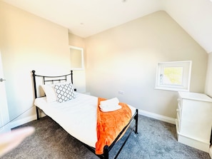 A bedroom with a bed, a nightstand, a dresser, and a window with a view. - 25A Moonstone House in Thetford (Thetford)