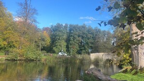 A serene riverside setting with a stone wall, lush greenery, and a clear blue sky. - 25A Moonstone House in Thetford (Thetford)