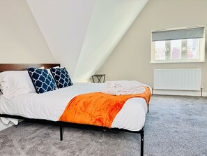 A bedroom with a bed, pillows, a blanket, a radiator, and a window. - 25A Moonstone House in Thetford (Thetford)