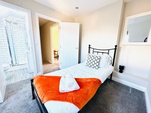 A bedroom with a bed, a white door, a mirror, and a carpeted floor. - 25A Moonstone House in Thetford (Thetford)