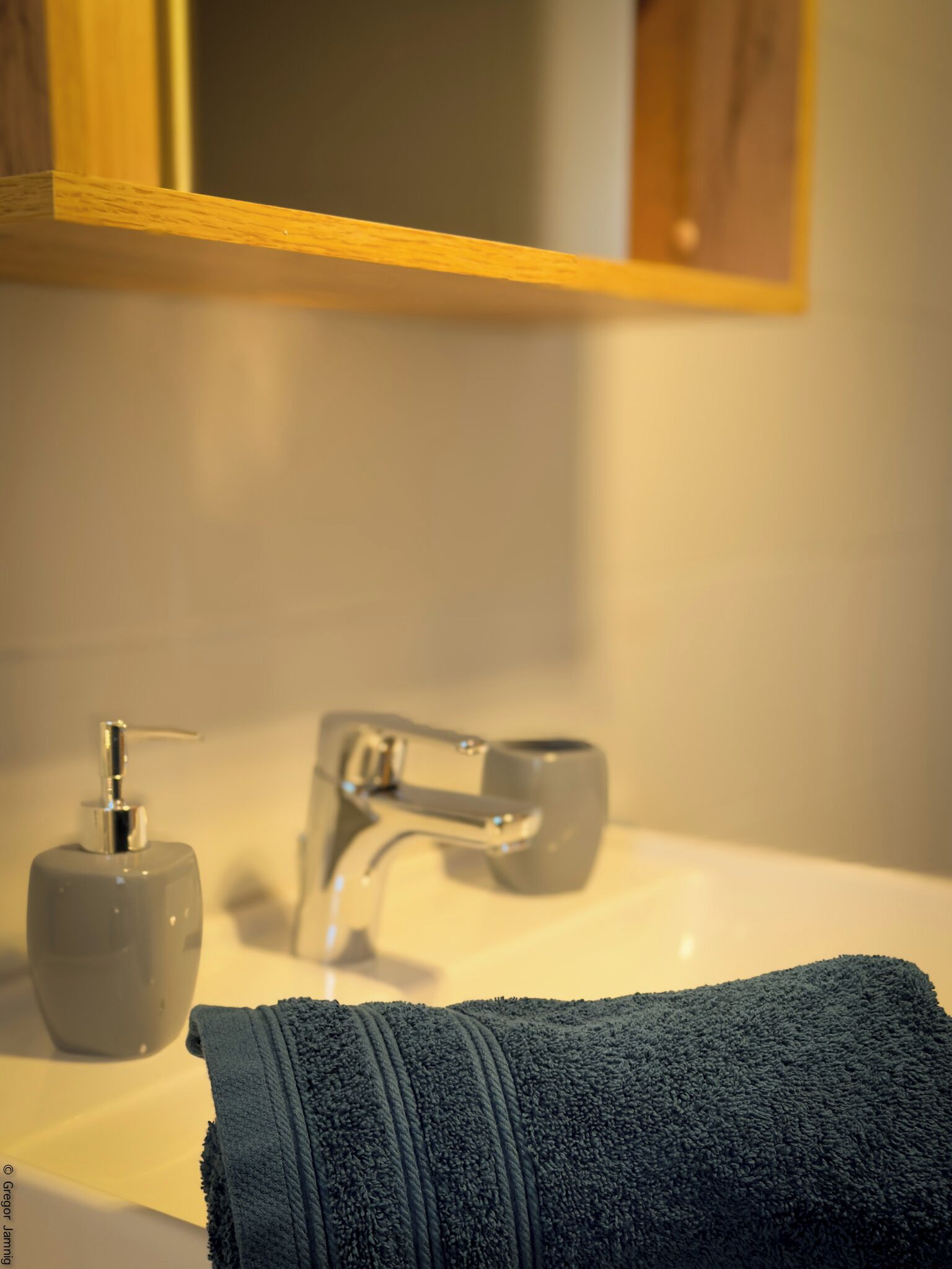 A bathroom with a sink, a faucet, and a soap dispenser.