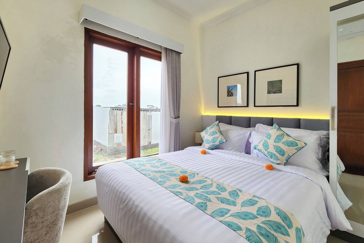 A hotel room with a large bed, a desk, and a view of the outside.