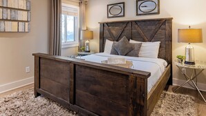 Un dormitorio con una cama de madera, una mesita de noche, una lámpara y un espejo instalado en la pared.