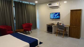 Una habitación de hotel con cama, escritorio, silla, televisor y armario.