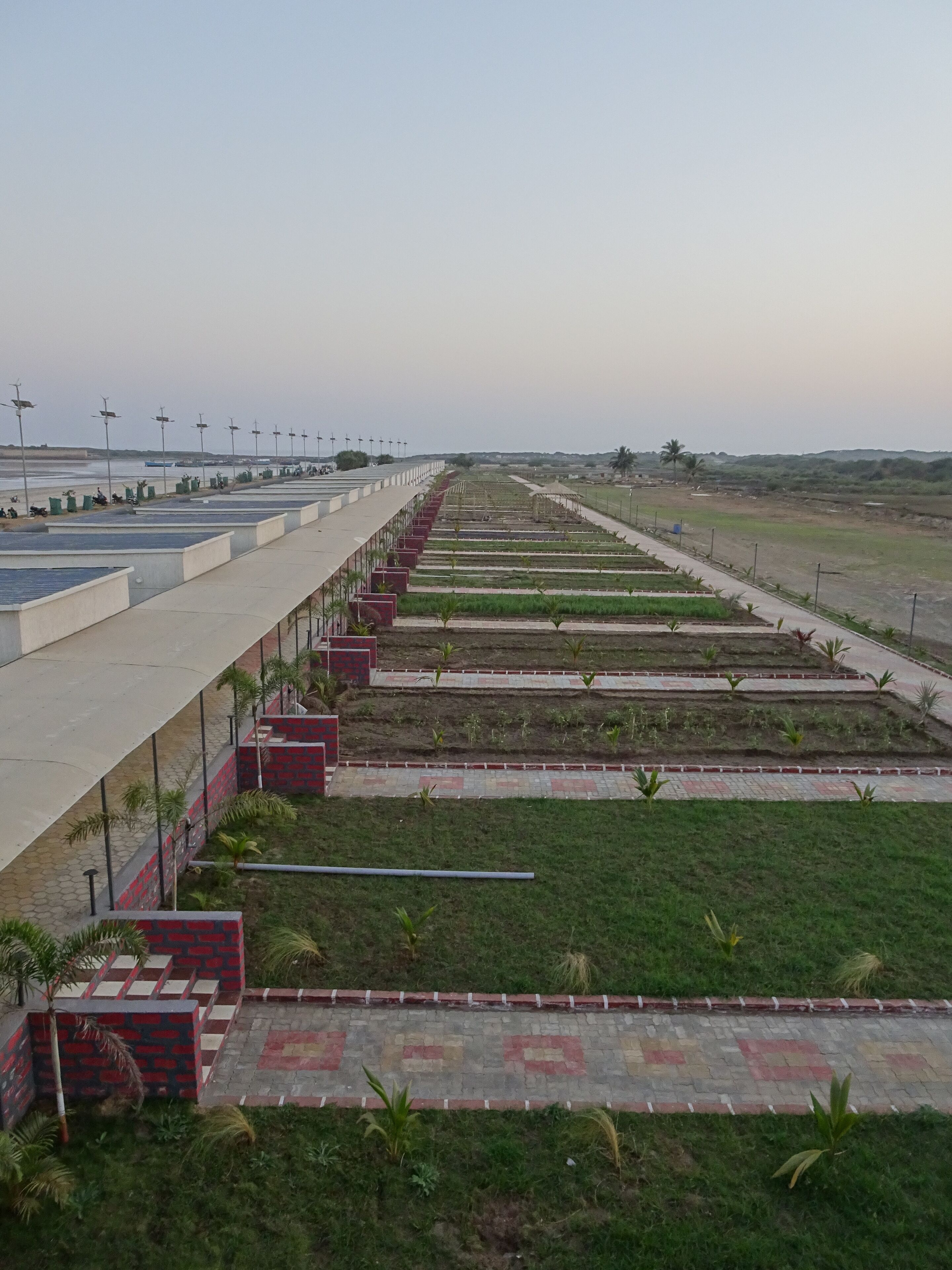 A long, straight pathway lined with small green plants and a series of red and white patterned tiles.