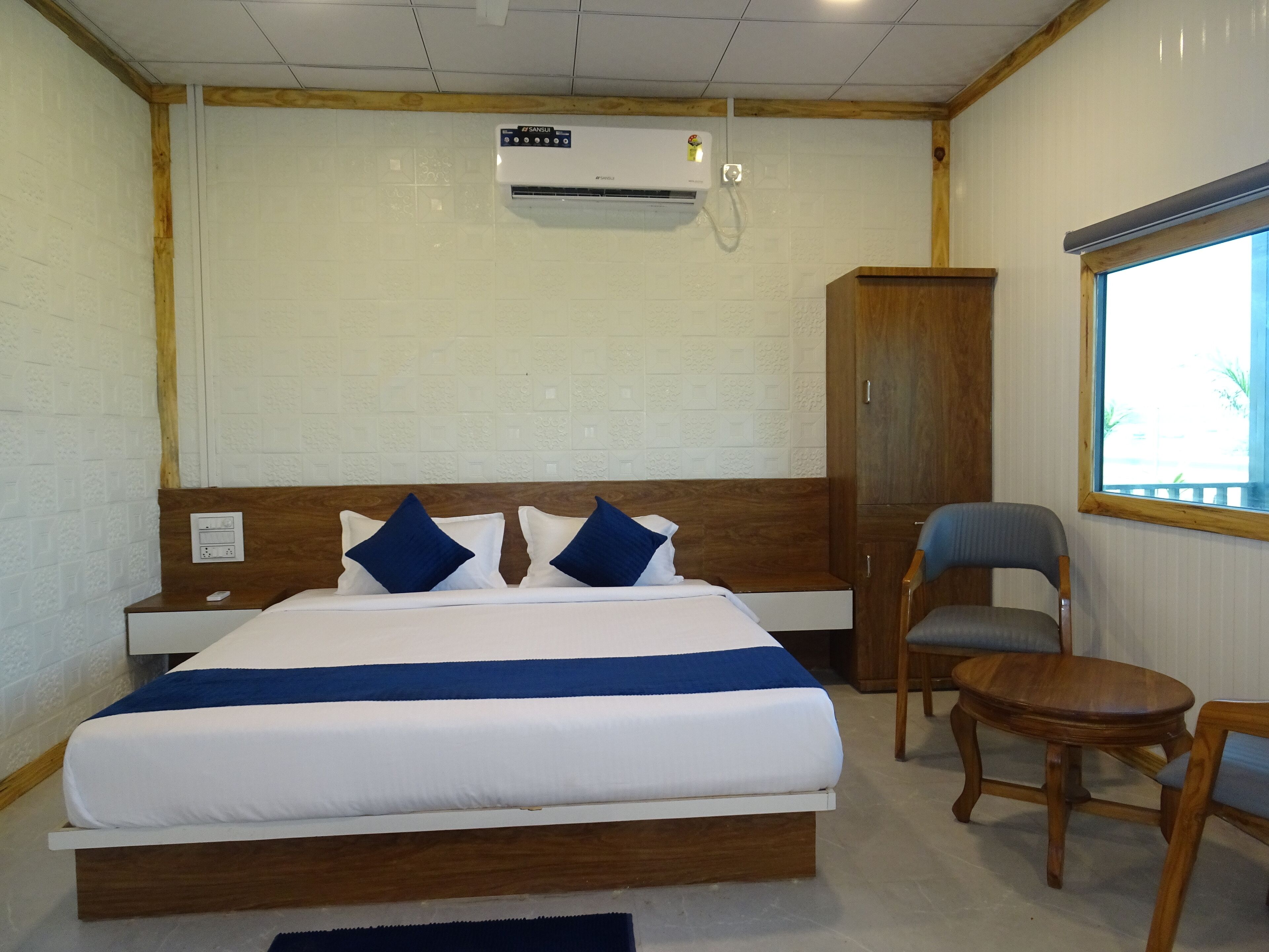 Una habitación de hotel con cama, armario de madera, escritorio y silla.