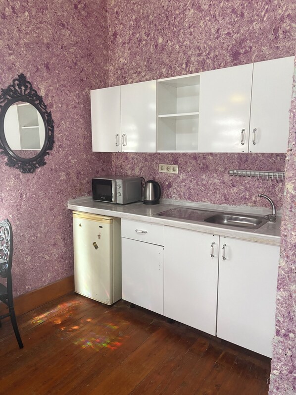 A compact kitchen with white cabinets, a microwave, a kettle, and a sink. - Taksim Cinar Suit (Istanbul)