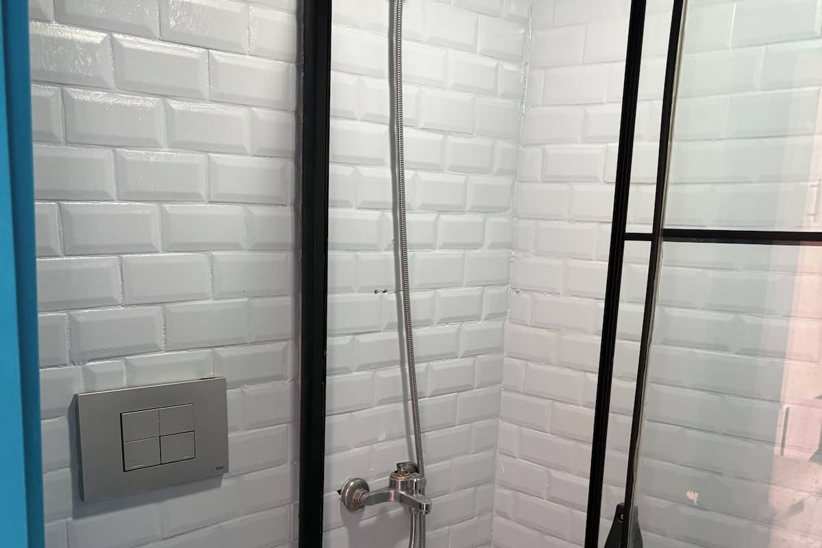 A bathroom with a white toilet, a shower with a glass door, and a wall-mounted control panel.