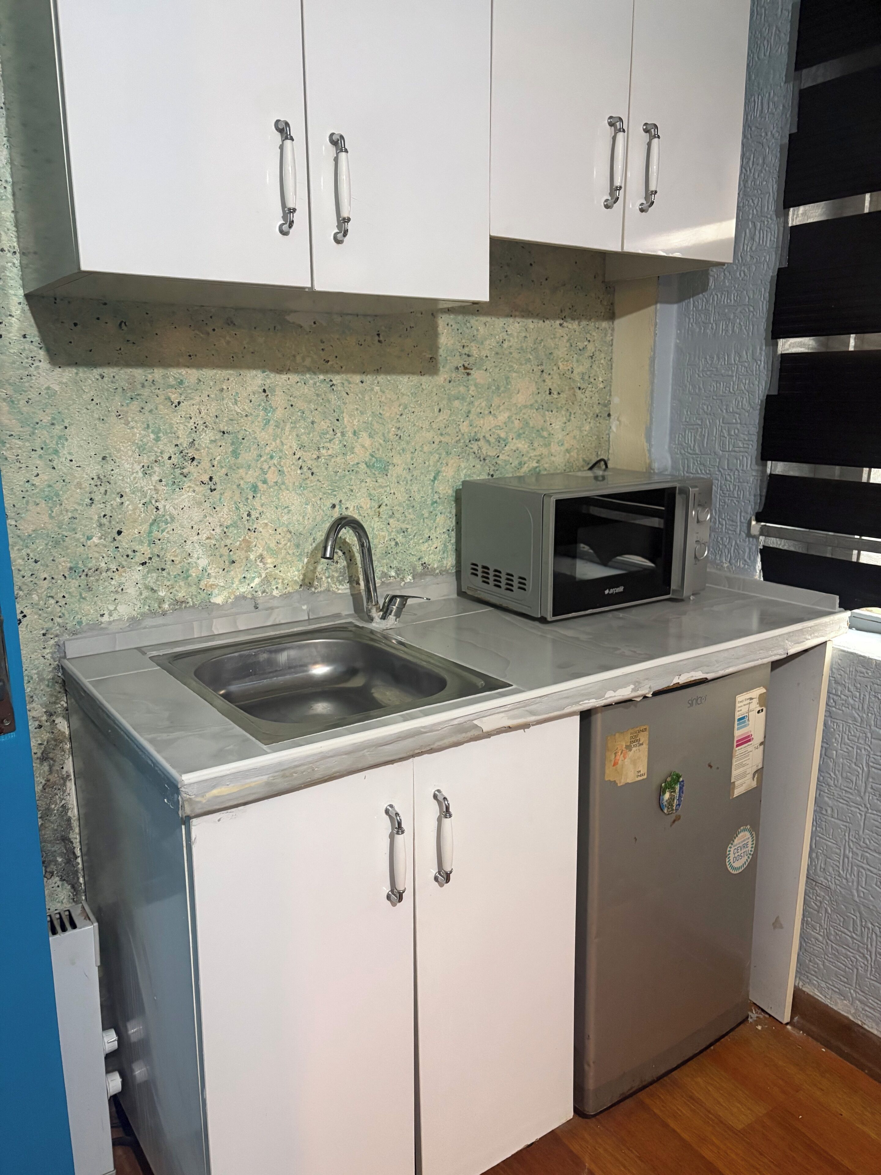 A kitchen with a sink, microwave, and white cabinets.