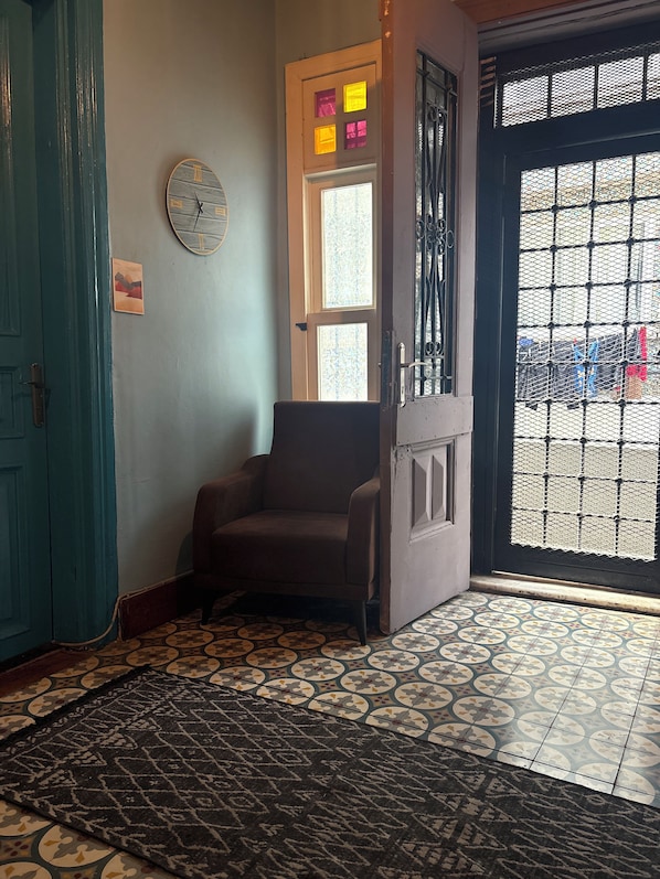 Quarto com piso estampado, uma cadeira, um relógio e uma porta com janela.