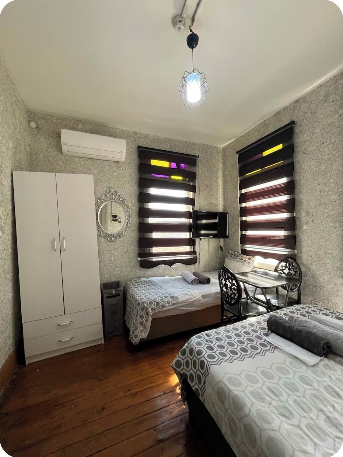 A bedroom with a bed, a desk, a chair, a wardrobe, and a ceiling light.