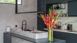 Una cocina moderna con encimera de mármol, pileta integrada y un jarrón con flores.