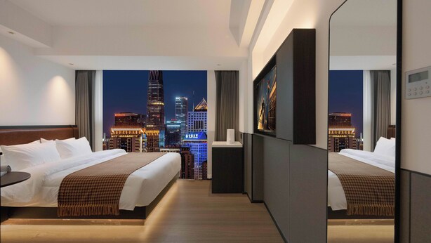 A hotel room with two beds, a small desk, and a view of a city skyline at night. - Mcsrh Hotel-Changsha Shaoshanbeilu (Changsha)