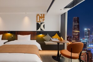 Habitación de hotel con una cama grande, una mesita, una silla y vistas a la ciudad.