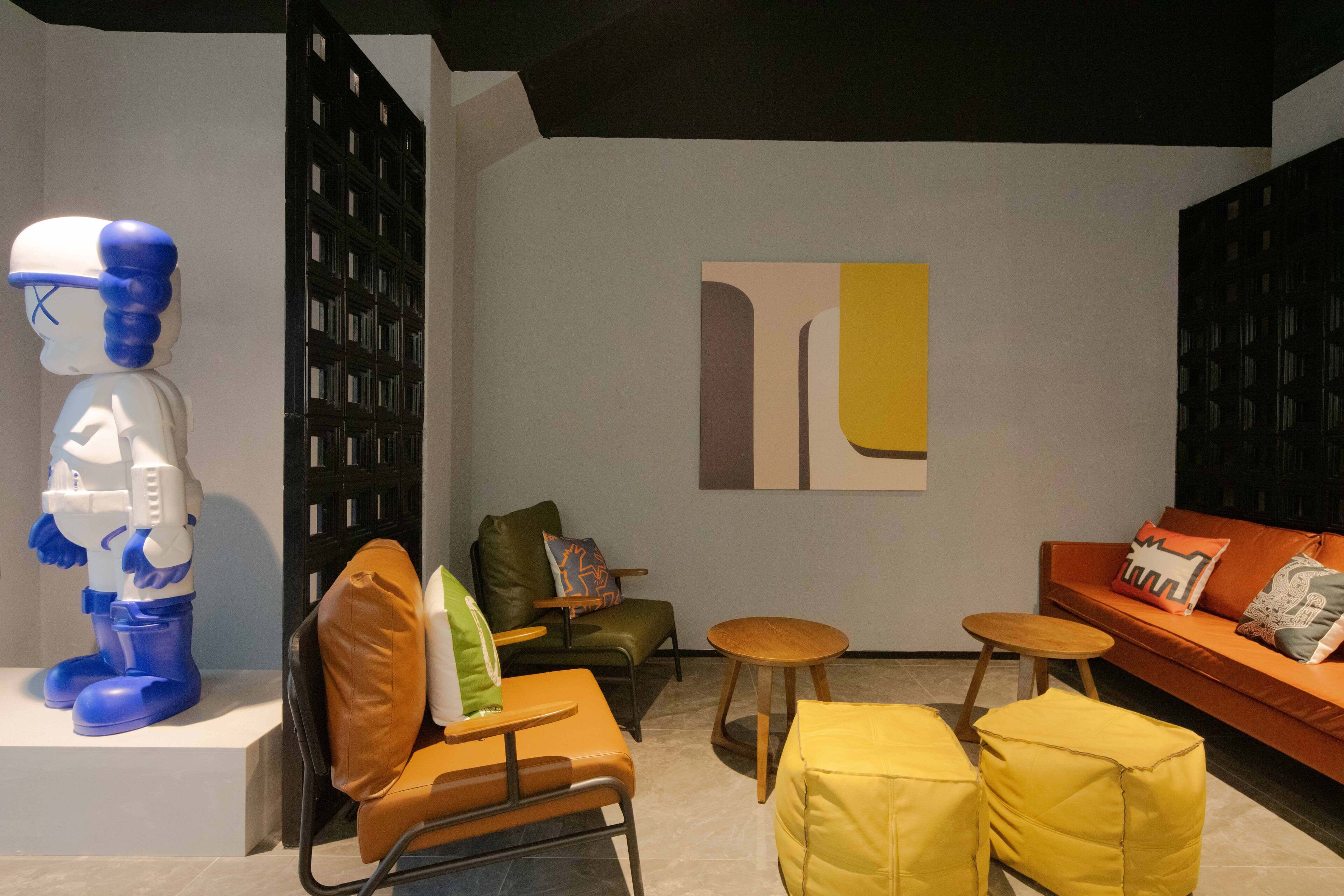 A modern living room with a robot sculpture, leather chairs, a wooden coffee table, and an orange sofa.