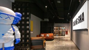 A modern interior with a robot figure, a lounge area with orange sofas, and a wall with 'CHANG SHA' signage. - Mcsrh Hotel-Changsha Shaoshanbeilu (Changsha)