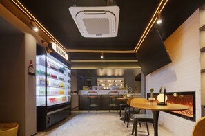 Un área de bar moderna con un dispensador refrigerado para bebidas, una mesa redonda con sillas y una chimenea.