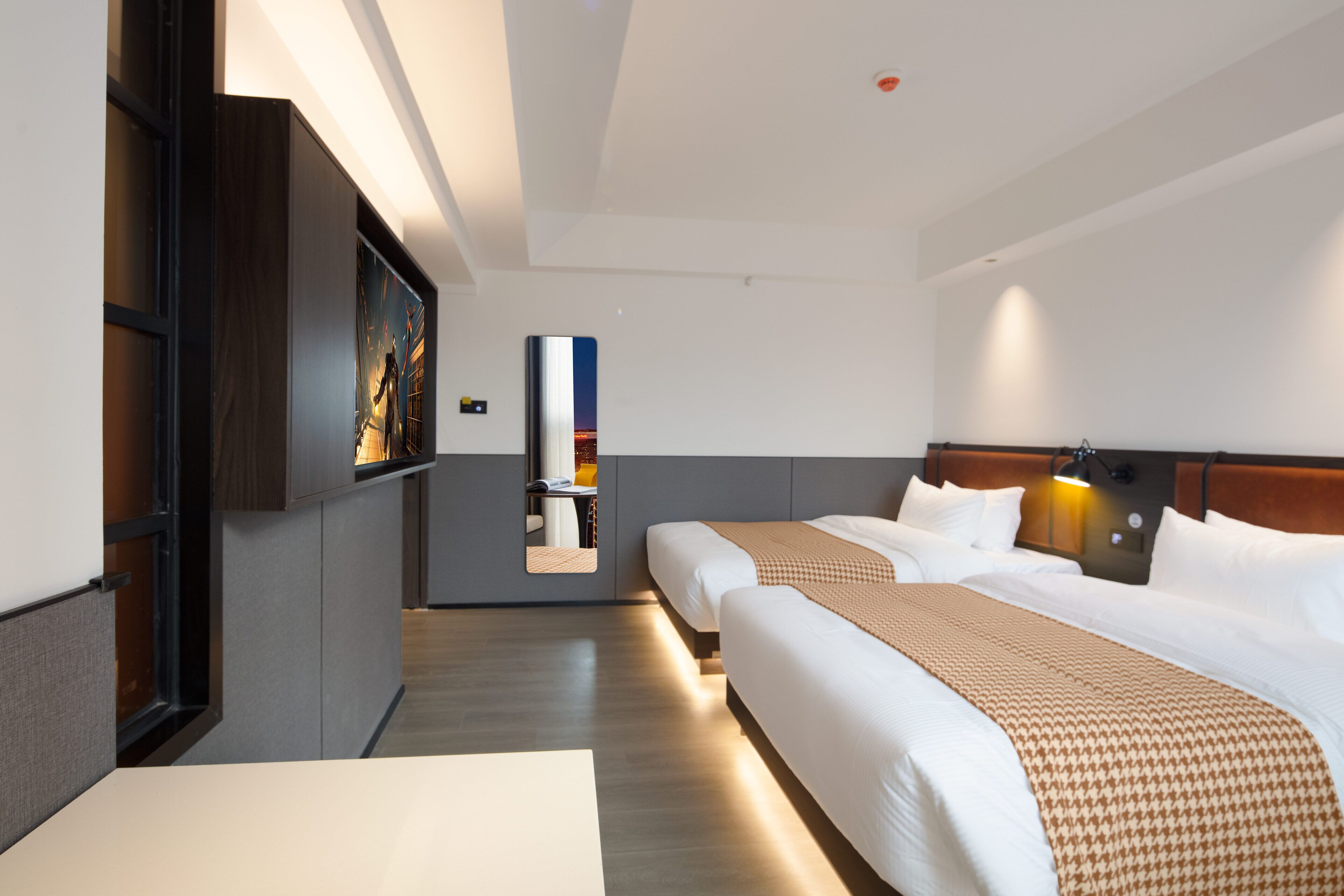 Een hotelkamer met twee bedden, een grote spiegel en een televisie aan de muur.