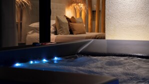 Een wellnessruimte met een jacuzzi, een bed met kussens en een lamp.