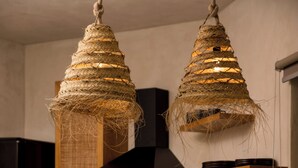 Een moderne keuken met een houten eiland, twee hangende lampen en een fruitschaal op het aanrecht.